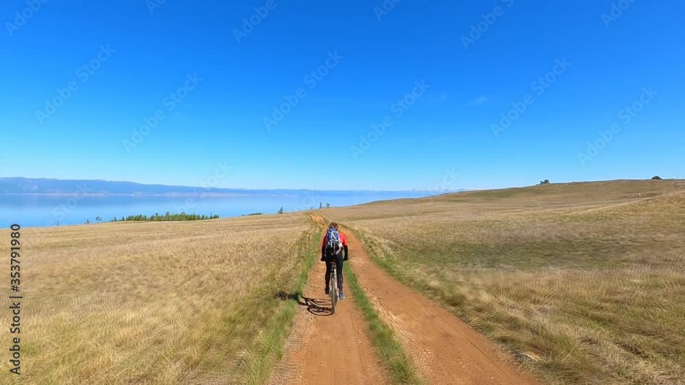 Young sports man riding bicycle at the rural road over field. Sporty guy cycling along country trail outdoor. Male cyclist riding bike in the countryside. Healthy active lifestyle Slow motion Young sports man riding bicycle at the rural road over field. Sporty guy cycling along country trail outdoor. Male cyclist riding bike in the countryside. Healthy active lifestyle Slow motion