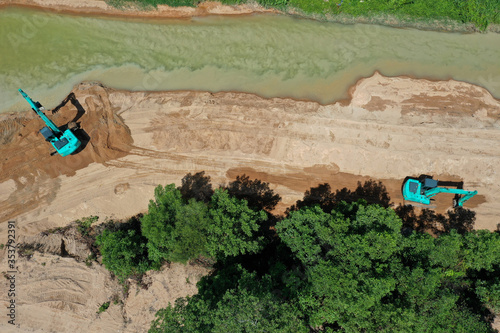 Environmental conservation issue. Machinery mining river, causing siltation and pollution  photo