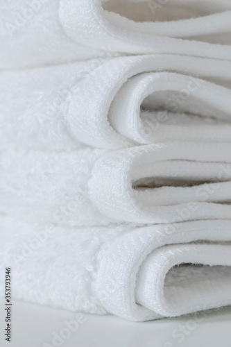 Stack of folded white towels on the table, closeup view, vertical view.