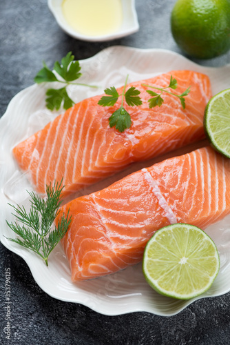 Close-up of raw sliced salmon fillet on ice with dill, parsley and lime, selective focus, studio shot