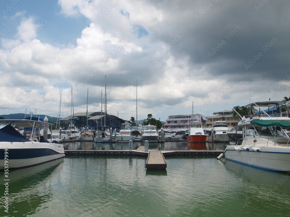 The yacht club marina resort, harbor view, motor and sail yachts. Cloudy weather. Tropical island. Sea harbor. Sailboat, motorboat for travel, rent and sale. Boat lagoon. Thailand, Phuket. Empty place
