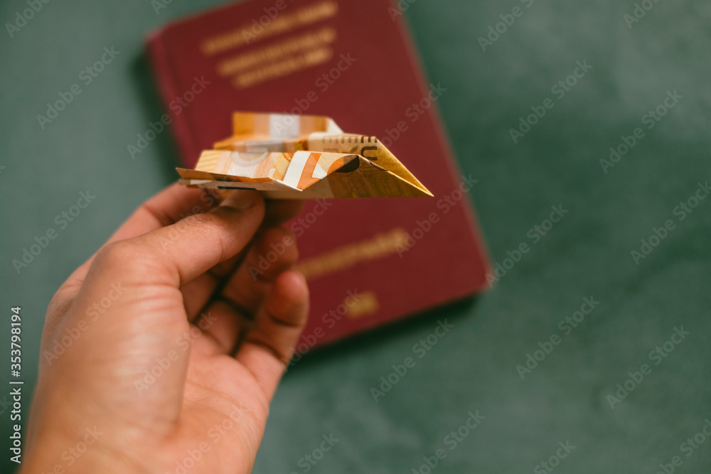 Fototapeta premium 50 Euro banknote folded in the shape of an airplane with a german passport. Low Cost Travel and Airline Concept. Travel Budget.