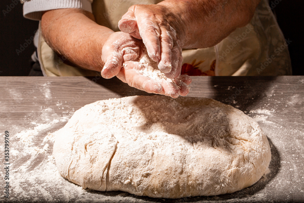 Hands of granny kneads dough. 80 years old woman hands kneading dough. Grandmother dough molding on table. homemade baking. Pastry and cookery