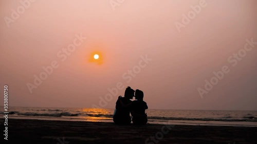 Romantic couple relaxing enjoying on beach looking at sunset with beautiful light and colors Couple sitting together on the beach during sunset 