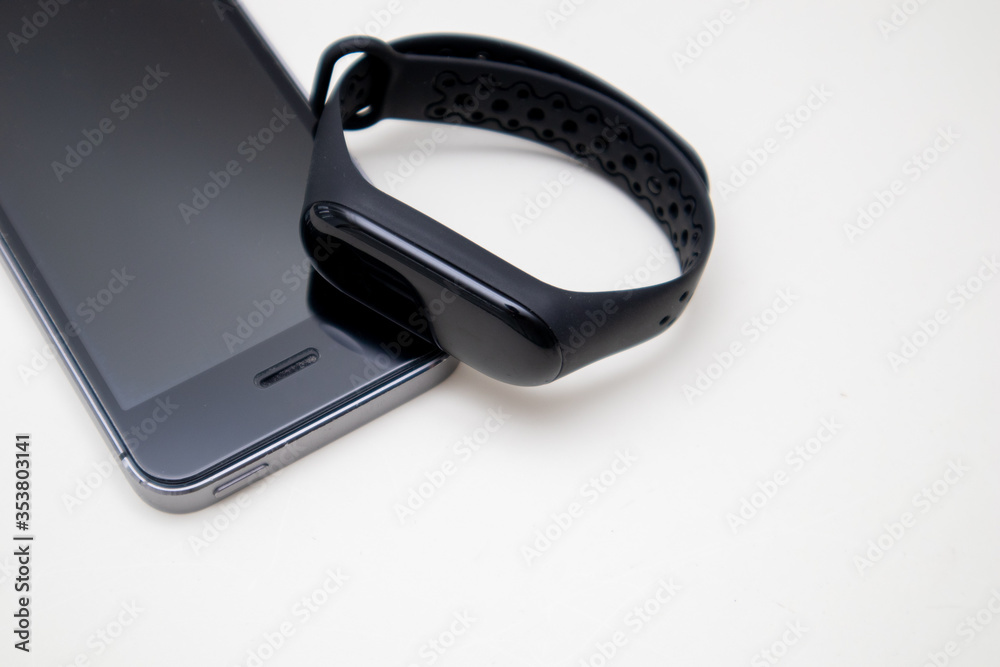 Black smartphone and fitness bracelet on a white background. Closeup, selective focus Black smartphone and fitness bracelet on a white background. Closeup, selective focus