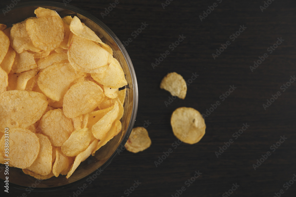 Crispy salted chips in the plate isolated on the black desk