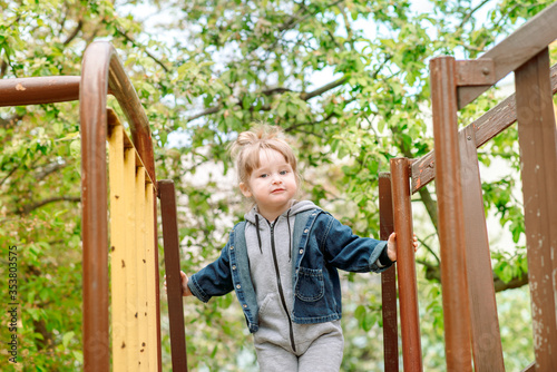 happy little toddler girl on the playground.Children's games in the park outdoors.Childhood joy and happiness.cheated, emotion perplexed.kids in kindergarten for a walk