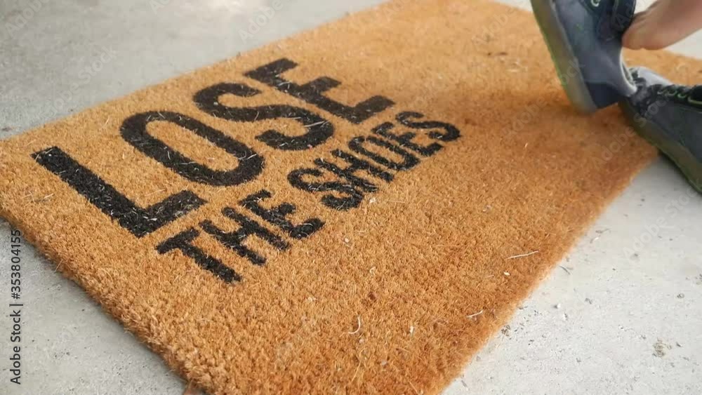 Kid taking shoes off on doormat.