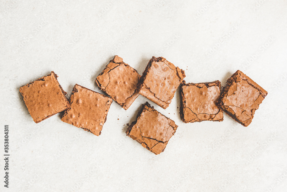 Top view of freshly baked home made brownie cake cut in squares over white rustic background.