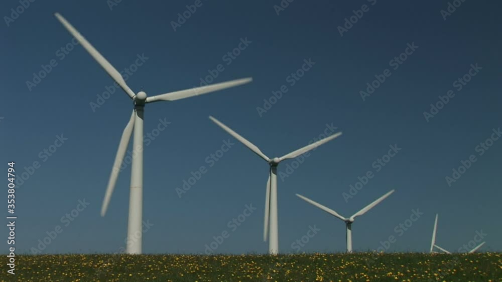 Wind turbines turning in the wind on a farm in England wild flowers UK Wind turbines turning in the wind on a farm in England wild flowers UK