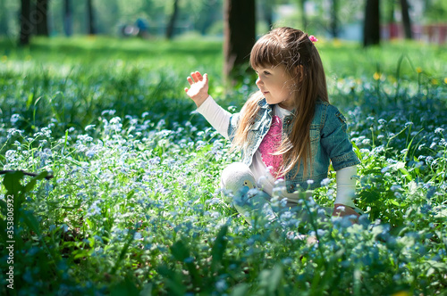 Portrait of a beautiful girlsitting in forget me not blue flowers