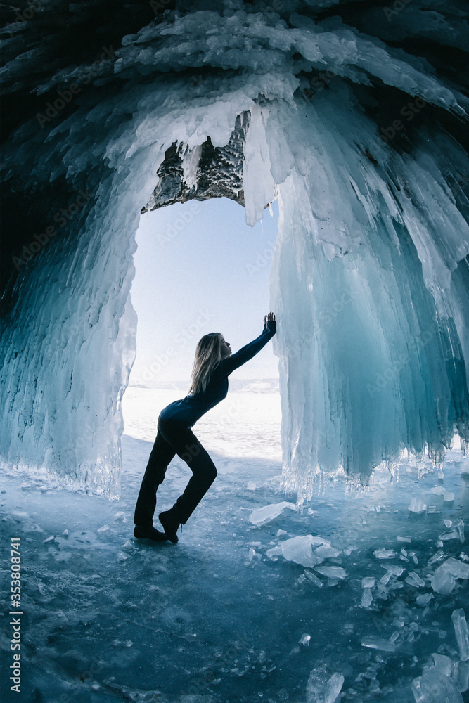 Fototapeta premium A person standing next to an ice waterfall cave
