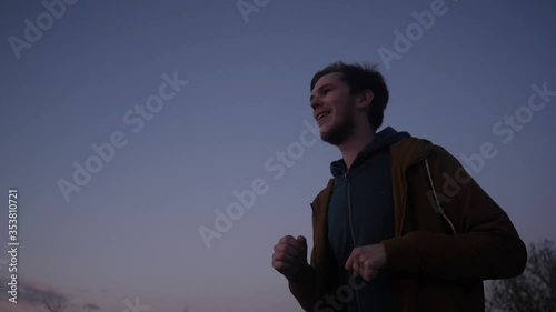 Evening jog along the road young man on sky background