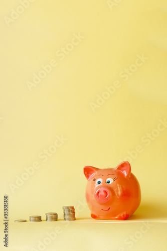 Piles of coins and piggy bank on a yellow background. Concept - saving money, accumulating finance, budget for a rainy day. photo