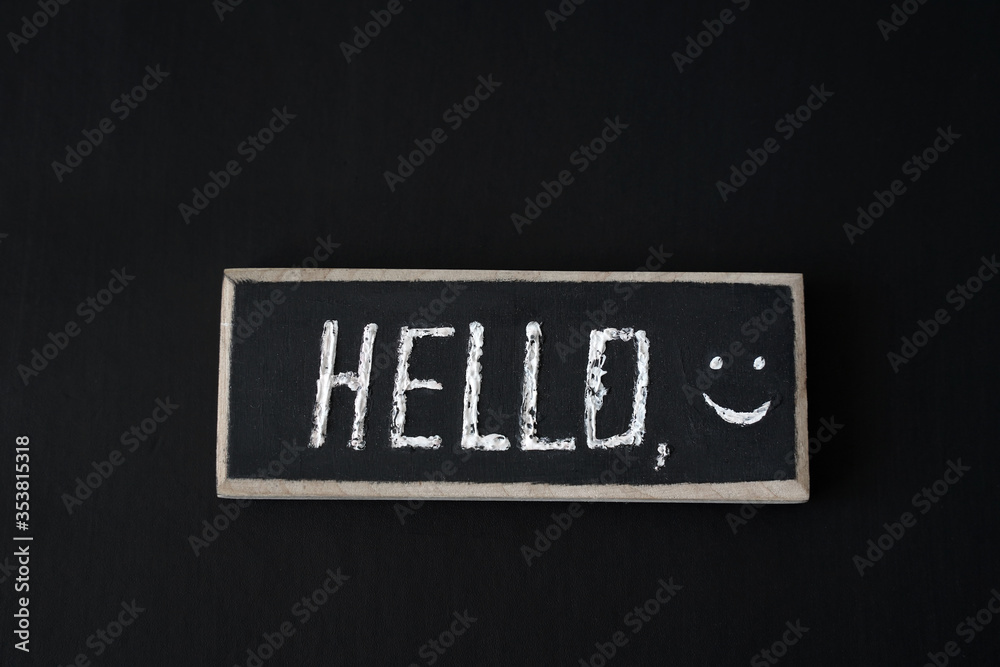 Wooden blackboard with hello and smiles on black background Wooden blackboard with hello and smiles on black background