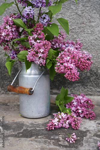 Lilac flowers in metal can on greey wall photo