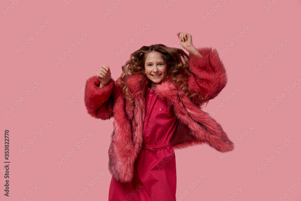 girl dances with long thick blond hair in a fashionable fur coat with pink fur