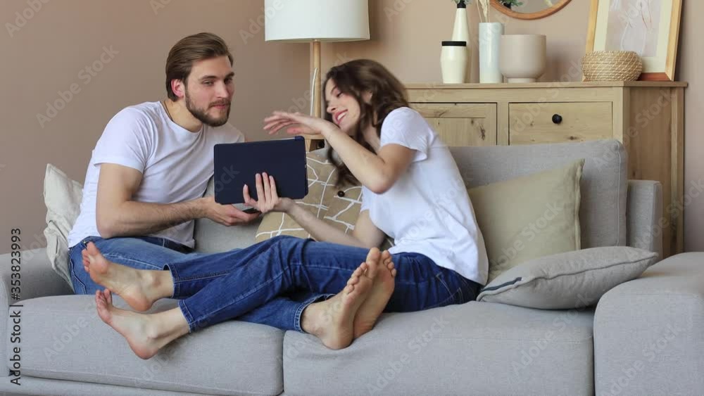 Happy young couple, woman showing her boyfriend something on a digital tablet while a young man watching there holds smartphone. Happy young couple, woman showing her boyfriend something on a digital tablet while a young man watching there holds smartphone.