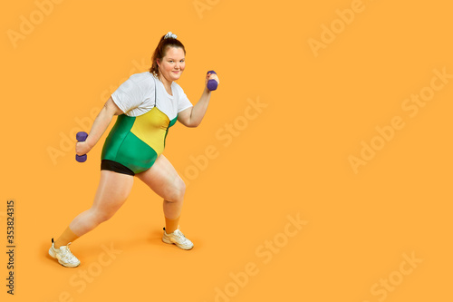 Bright cheerful fat girl is engaged in sports and looks at the camera.