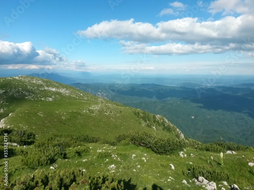 beautiful landscape seen from top of the green mountain in summer season. horizon line on sunny day with blue sky and fluffy clouds