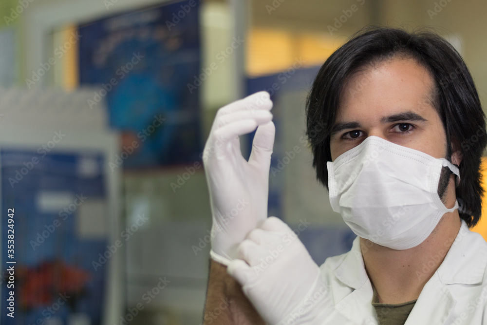 Researcher putting white nitrile surgical gloves to start an experiment in a biotechnology laboratory Researcher putting white nitrile surgical gloves to start an experiment in a biotechnology laboratory