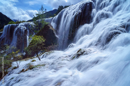 Beautiful and fresh scenery at waterfalls with massive cascade  green algae  reflection and trees.