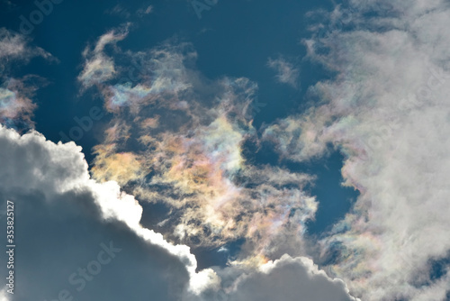 Colorful fluffy iridescent cloud on deep blue sky
