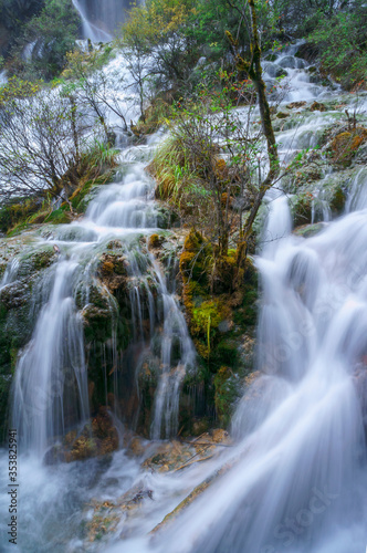 Beautiful and fresh scenery at waterfalls with massive cascade  green algae  reflection and trees.