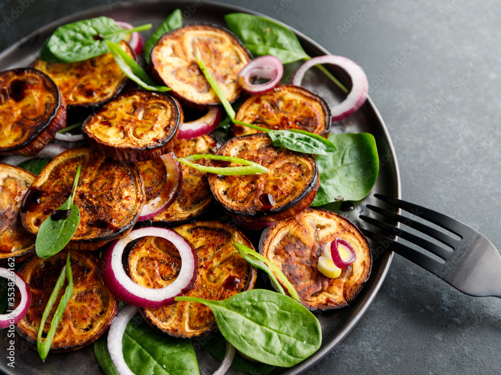 Salad with grilled eggplant, spinach, purple onion and sauce on a dark table. Salad with grilled eggplant, spinach, purple onion and sauce on a dark table.