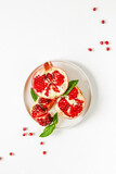 Red pomegranate on a white background. Grenades are scattered on the table. Pomegranate berries glisten on a white background.