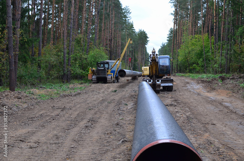 Pipelaying crane lowers a section of pipe into a trench. Construction of gas pipeline to new LNG plant. Side boom operation install natural gas pipeline and oil pipes. Small sharpness, granularity 