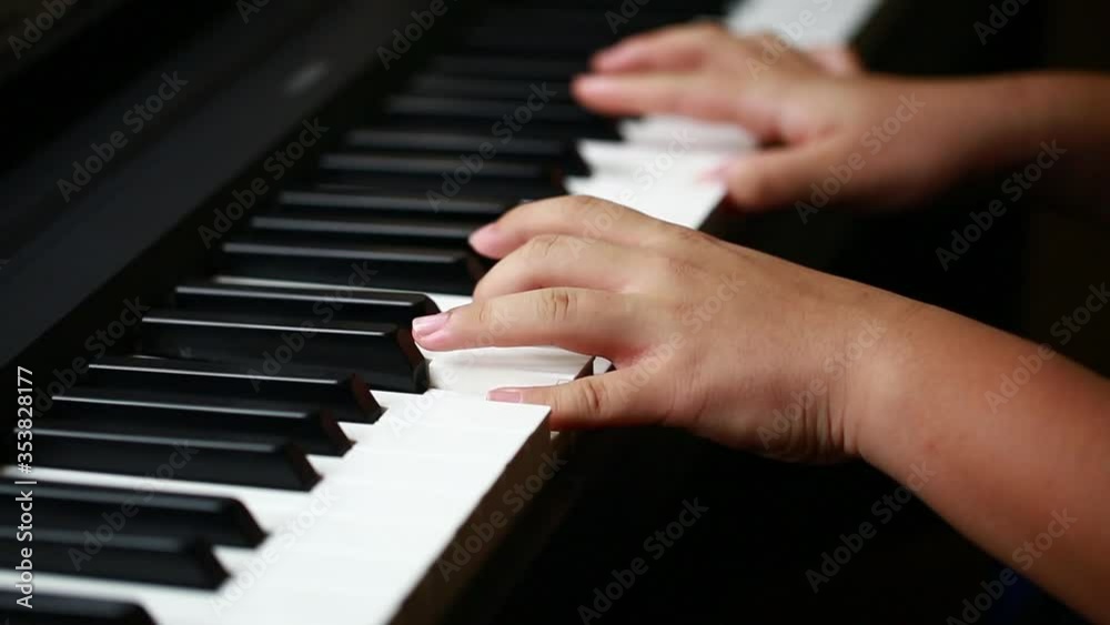 Selective focus to kid fingers and piano key to play the piano. There are musical instrument for concert or learning music. Close up hand of child musician playing the piano on stage. Selective focus to kid fingers and piano key to play the piano. There are musical instrument for concert or learning music. Close up hand of child musician playing the piano on stage.