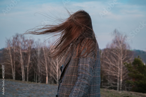 фотографія Young woman standing on street with hair blown by the wind, covering her face