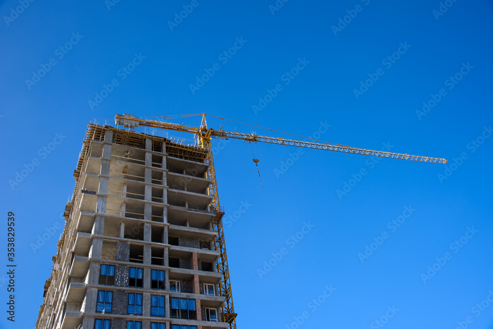 Tower crane working at construction site on blue sky background with white clouds. Construction process of the new residential buildings. Installing double glazed windows Tower crane working at construction site on blue sky background with white clouds. Construction process of the new residential buildings. Installing double glazed windows