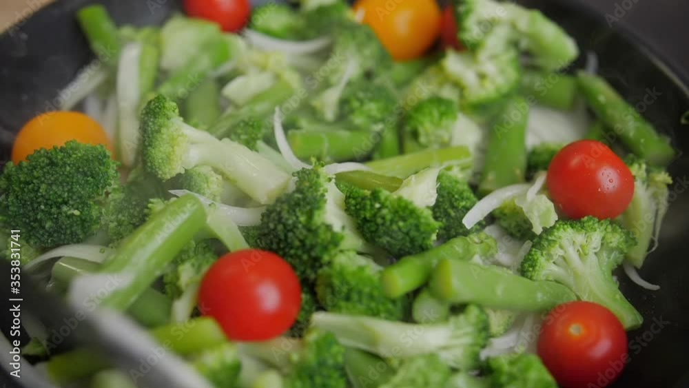 Onions, broccoli and beans are fried in a pan, vegetables are cooking Onions, broccoli and beans are fried in a pan, vegetables are cooking
