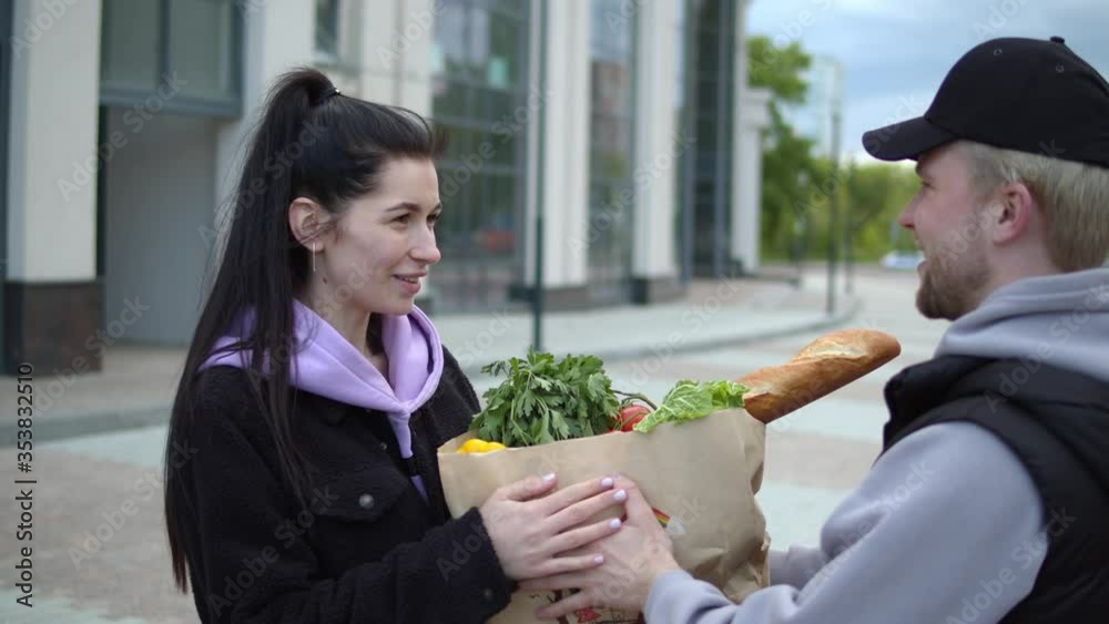 Portrait of delivery man wearing cap and medical mask carrying packet with fresh food. Order products online stay at home Courier bringing grocery to house, door to door delivery during quarantine. Portrait of delivery man wearing cap and medical mask carrying packet with fresh food. Order products online stay at home Courier bringing grocery to house, door to door delivery during quarantine.