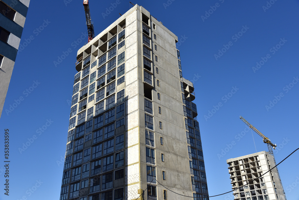 Tower crane constructing a new residential building at a construction site. Renovation program, development, concept of the buildings industry. Tower crane constructing a new residential building at a construction site. Renovation program, development, concept of the buildings industry.