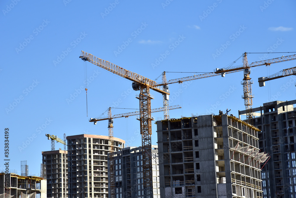 Tower cranes constructing a new residential build. Luffing jib tower crane and workers being poured concrete into formwork of building at construction site. Cement pouring Tower cranes constructing a new residential build. Luffing jib tower crane and workers being poured concrete into formwork of building at construction site. Cement pouring