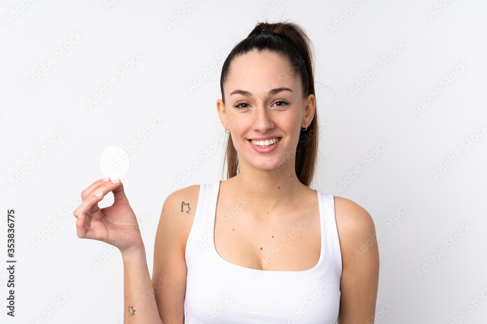 Young brunette woman over isolated white background with cotton pad for removing makeup from her face and smiling Young brunette woman over isolated white background with cotton pad for removing makeup from her face and smiling