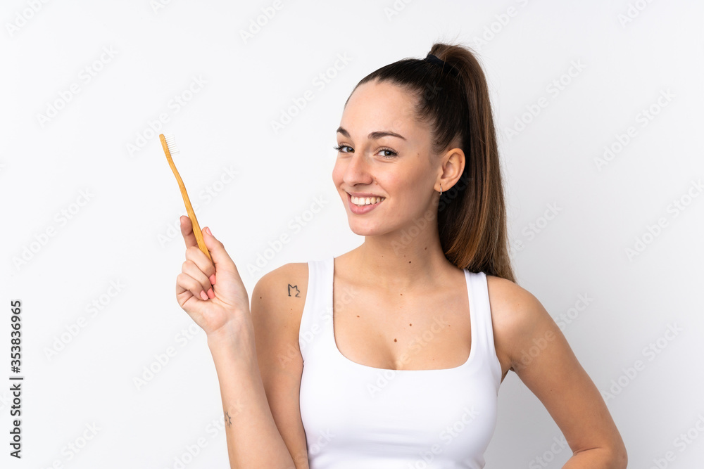 Young brunette woman over isolated white background with a toothbrush Young brunette woman over isolated white background with a toothbrush