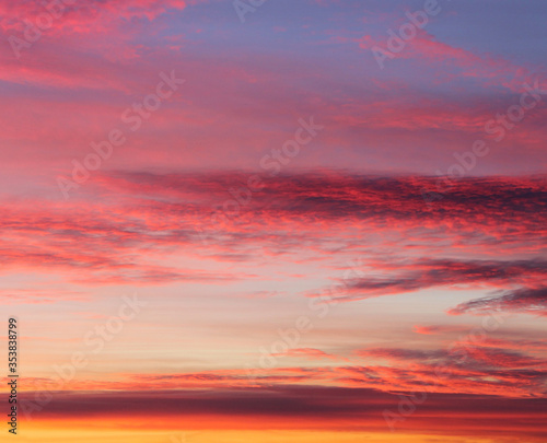 Dramatic sky at sunset, natural color of evening cloudscape with setting sun rays highlighting clouds. Sky and clouds in bright rainbow colors, colorful sky in dusk. Majestic purple sky