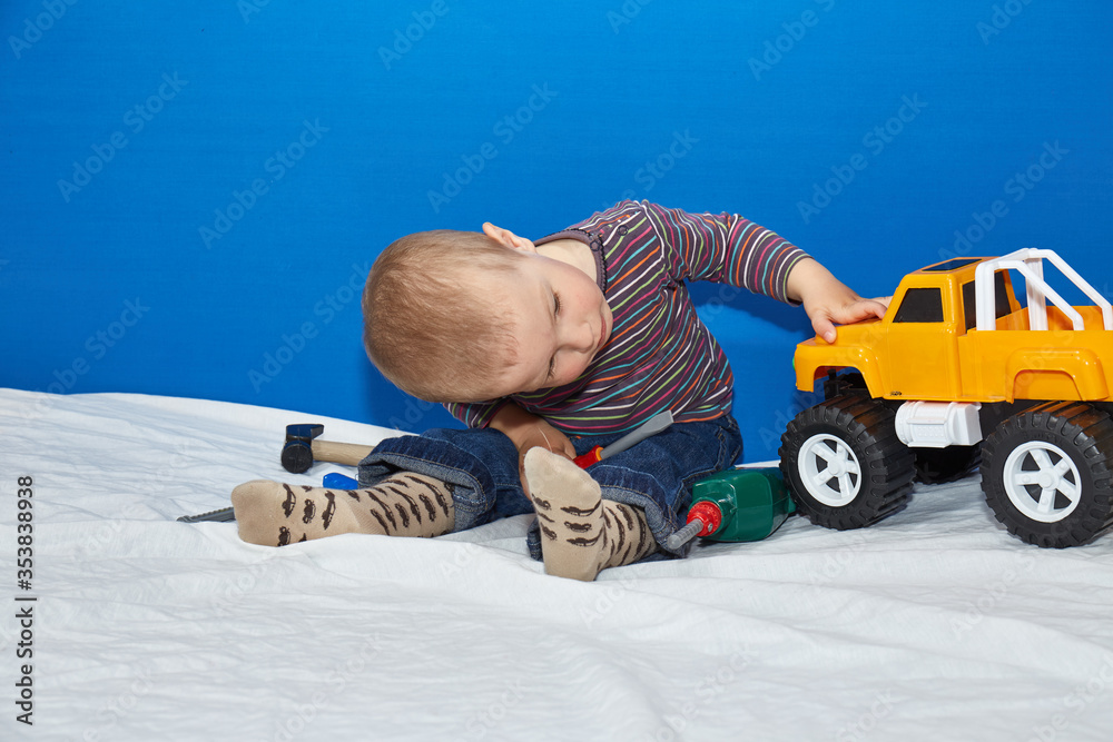 Fototapeta premium The child looks at a toy car on a blue background