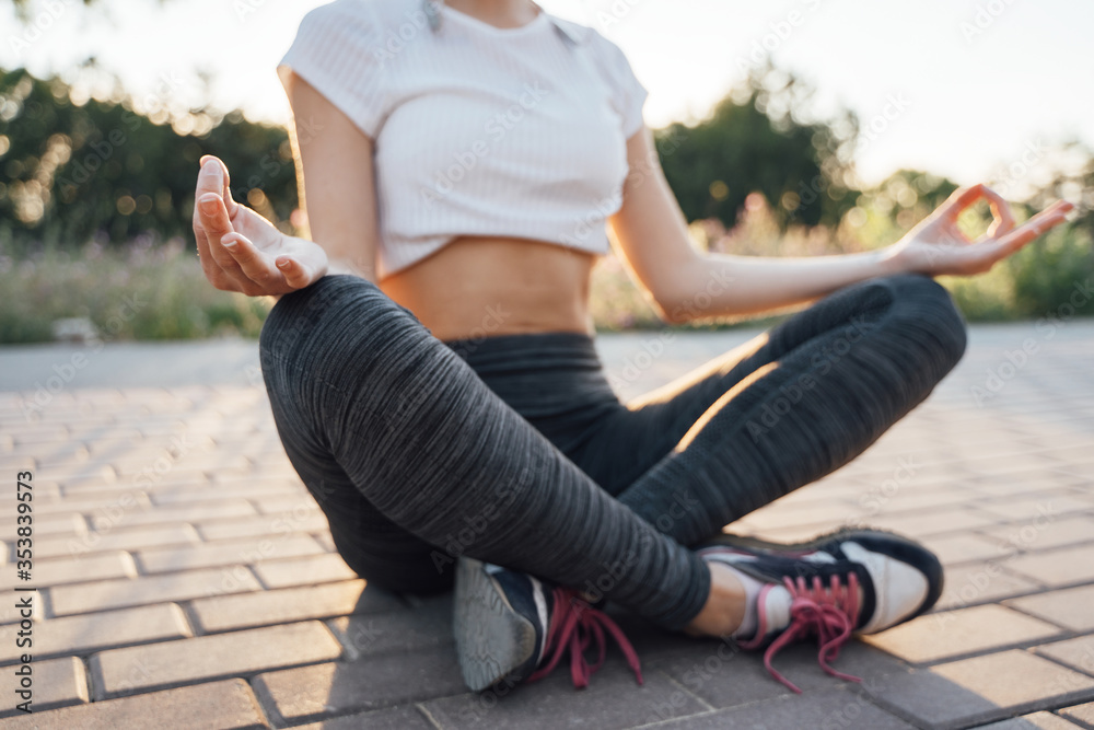 A girl at sunset sits in a lotus pose with headphones in her ears close-up focus on her hand A girl at sunset sits in a lotus pose with headphones in her ears close-up focus on her hand
