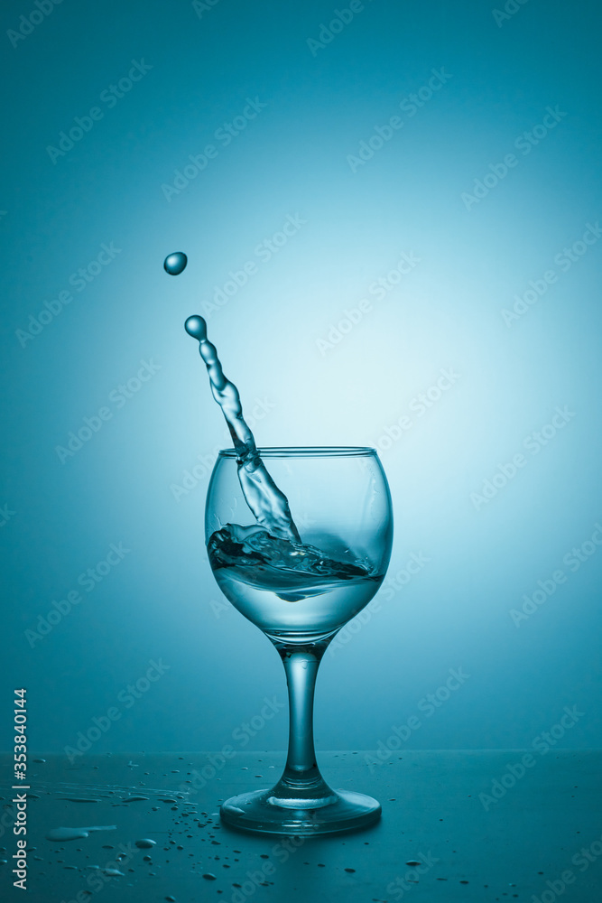 Water splashing in the luxury wine glass close up. Concept of good healthy and refreshment. Copy space on left side on the image.