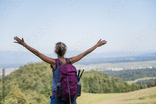 Young female hiker enjoying life with arms raised high