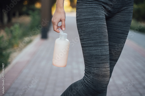 Girl in gray leggings holds a pink water bottle close-up