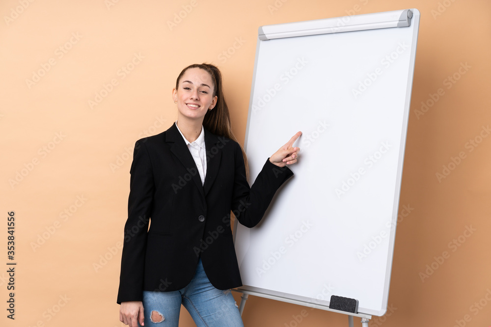 Young business woman over isolated background giving a presentation on white board Young business woman over isolated background giving a presentation on white board