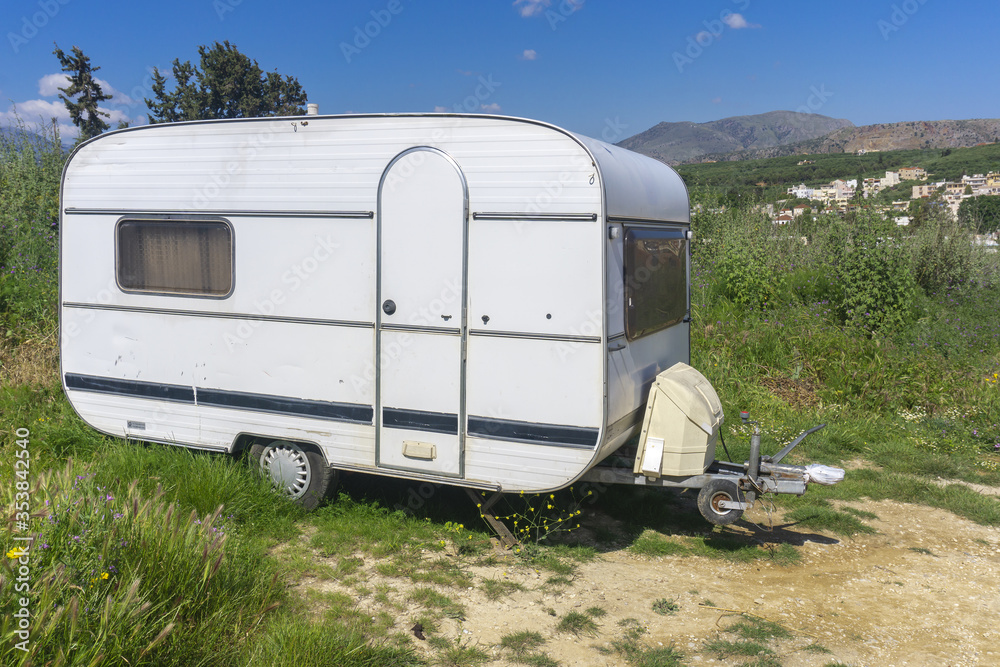 White caravan or camper trailer parked on country road in mountains. Camping travel, countryside travel.