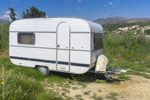 White caravan or camper trailer parked on country road in mountains. Camping travel, countryside travel.