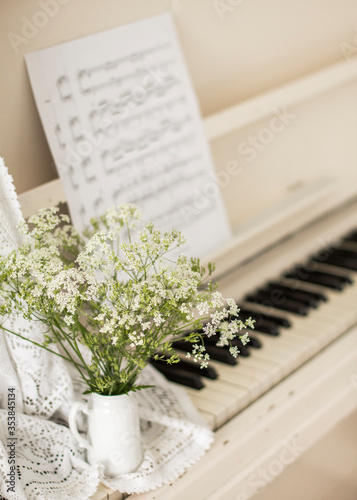 bouquet wildflowers on white piano with notes. Retro photo